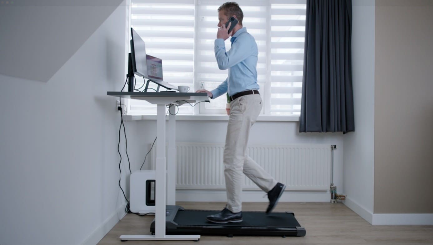 Werknemer loop op loopband onder bureau